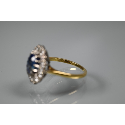 375 - An oval sapphire and diamond ring, the claw set blue sapphire surrounded by sixteen claw set diamond... 