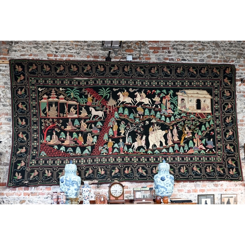 A late 19th century Burmese black felt textile Kalaga, applied with cotton and felt animals and figures in various pursuits with metallic threads embellished with sequins and beads, probably classical play scenes from Jataka or Ramayana within repeating Garuda bird border, 385 cm x 210 cm c/w Joss Graham Oriental Textiles Invoice dated 11/11/94