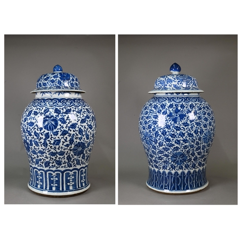 Two large 19th century Chinese blue and white temple jars and domed covers, painted in rich tones of underglaze blue with a similar continuous lotus scroll design between ruyi-head and lappet banding, late Qing dynasty, 64 cm and 62 cm high 