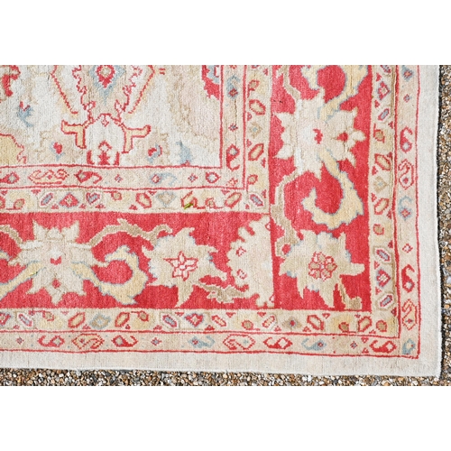 750 - A contemporary pale camel and red ground Agra carpet, traditional repeating design, 314 cm x 210 cm