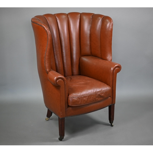 811 - An antique mahogany framed rib-backed studded brown leather wing armchair, raised on square mahogany... 