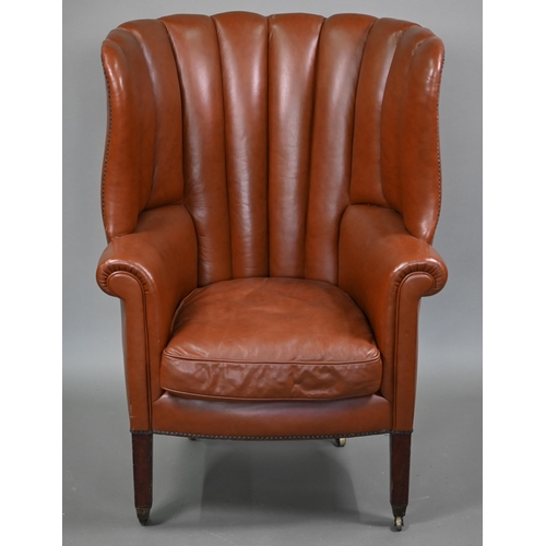 811 - An antique mahogany framed rib-backed studded brown leather wing armchair, raised on square mahogany... 