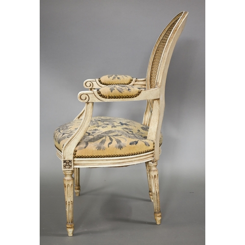 837 - A pair of French ivory painted cane panel backed salon elbow chairs, with floral needlepoint sprung ... 