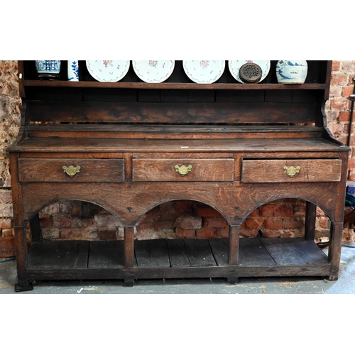 851 - An 18th century Georgian oak high dresser, the wide plank backed rack with three tiers, over a stage... 