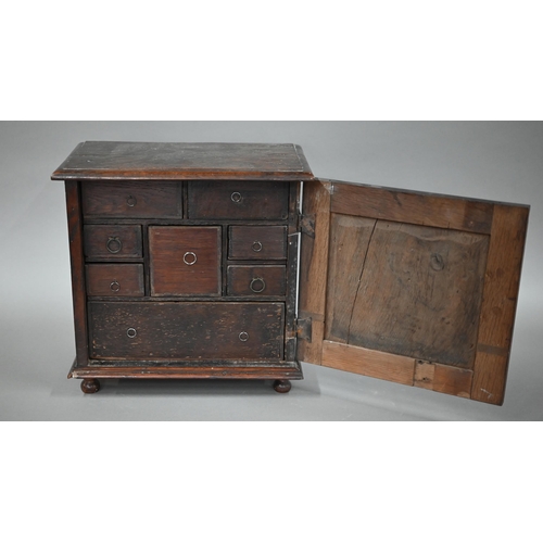 872 - An 18th century oak table cabinet, the door with applied moulded detail enclosing an arrangement of ... 