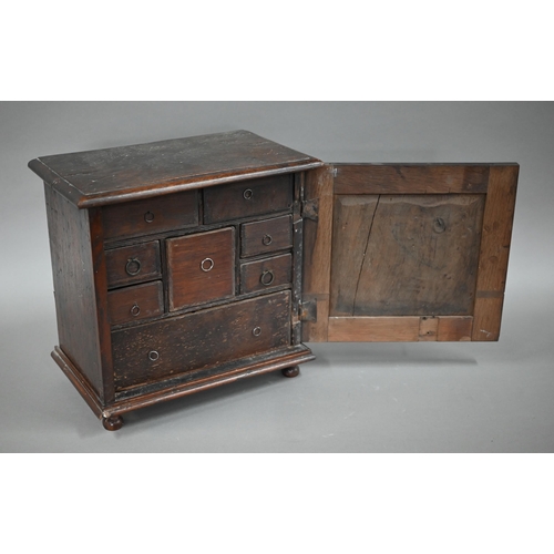 872 - An 18th century oak table cabinet, the door with applied moulded detail enclosing an arrangement of ... 