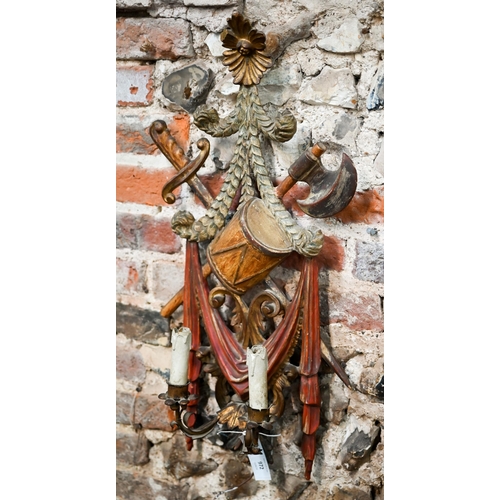 972 - A continental carved giltwood and polychrome twin branch wall sconce, with drum, sword an axe design... 