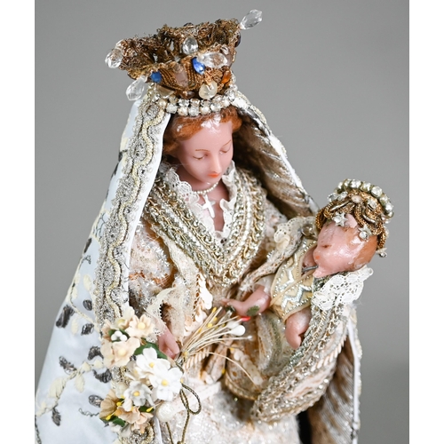 981 - A wax Madonna and Child figure in ornate embroidered and sequined robes, the plinth inscribed 'Monst... 