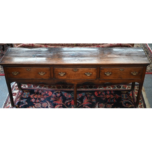 804 - A late 17th/18th century oak three drawer low dresser, with shaped frieze and raised on three chamfe... 