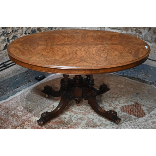 878 - A Victorian figured walnut oval tilt top loo/breakfast table, raised on four turned columns to mould... 