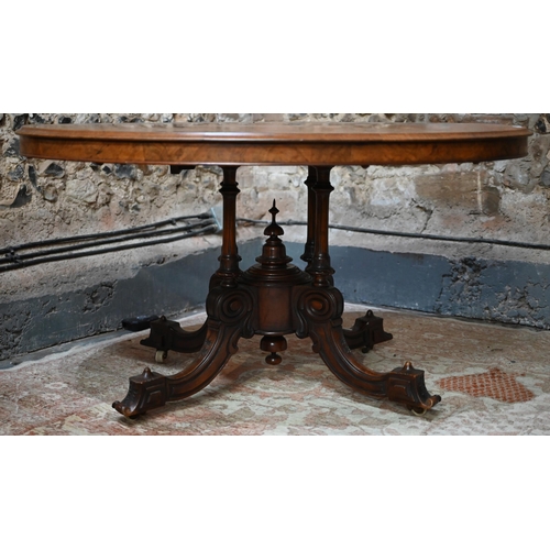 878 - A Victorian figured walnut oval tilt top loo/breakfast table, raised on four turned columns to mould... 