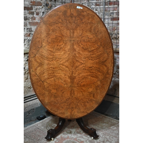 878 - A Victorian figured walnut oval tilt top loo/breakfast table, raised on four turned columns to mould... 