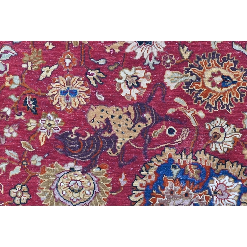 724 - A large Indo Persian Tabriz carpet, mid 20th century, the all-over floral and animal design on red-b... 