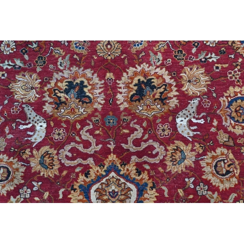 724 - A large Indo Persian Tabriz carpet, mid 20th century, the all-over floral and animal design on red-b... 