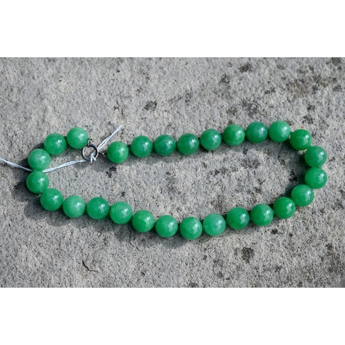 352 - A uniform row of green jade beads, double knotted throughout, each bead approx 1.4 cm diam, 41 cm lo... 