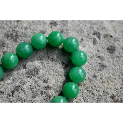 352 - A uniform row of green jade beads, double knotted throughout, each bead approx 1.4 cm diam, 41 cm lo... 