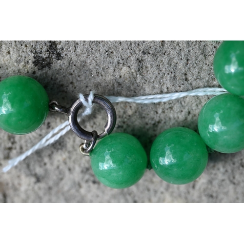 352 - A uniform row of green jade beads, double knotted throughout, each bead approx 1.4 cm diam, 41 cm lo... 