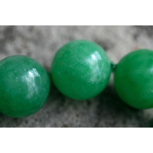 352 - A uniform row of green jade beads, double knotted throughout, each bead approx 1.4 cm diam, 41 cm lo... 