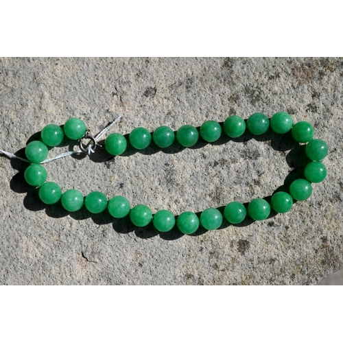 352 - A uniform row of green jade beads, double knotted throughout, each bead approx 1.4 cm diam, 41 cm lo... 