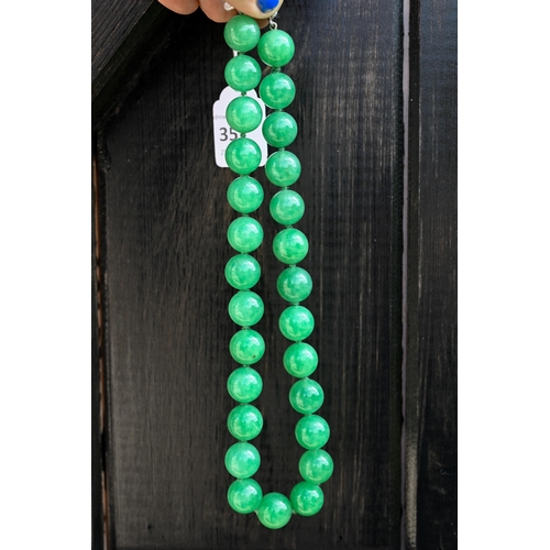 352 - A uniform row of green jade beads, double knotted throughout, each bead approx 1.4 cm diam, 41 cm lo... 