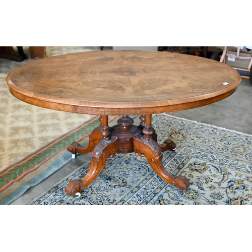 104 - A Victorian walnut and satin inlaid loo table with oval quarter-veneered top on four turned pillars ... 