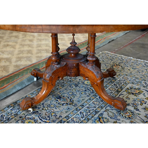 104 - A Victorian walnut and satin inlaid loo table with oval quarter-veneered top on four turned pillars ... 