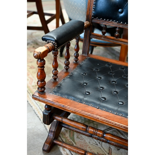 140 - # An early 20th century walnut framed American rocking chair, in buttoned black leatherette