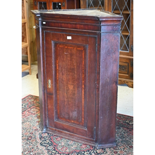 154 - An antique oak hanging corner cupboard with panelled door enclosing shelved interior, 80 cm wide x 1... 