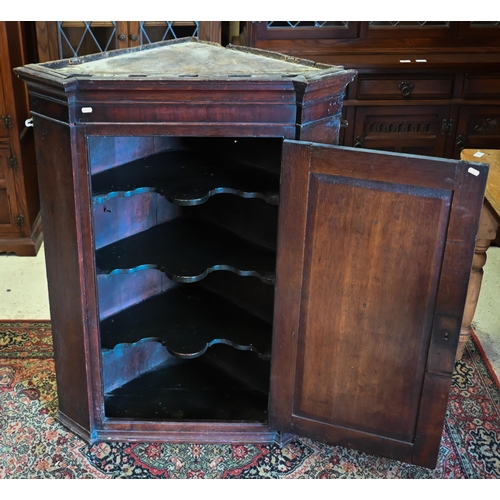 154 - An antique oak hanging corner cupboard with panelled door enclosing shelved interior, 80 cm wide x 1... 