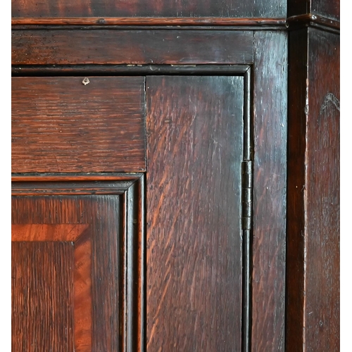 154 - An antique oak hanging corner cupboard with panelled door enclosing shelved interior, 80 cm wide x 1... 