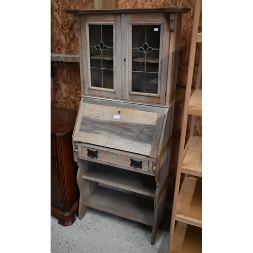 159 - An Arts & Crafts limed oak bureau display cabinet with stained and leaded glass doors in the Lib... 