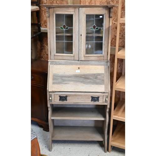 159 - An Arts & Crafts limed oak bureau display cabinet with stained and leaded glass doors in the Lib... 