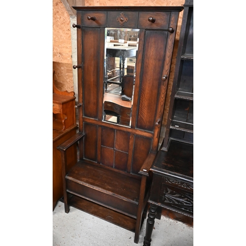 202 - A panelled oak hall bench, the raised back fitted with bevelled mirror and eight coat/hat pegs, 80 x... 