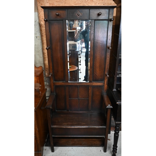 202 - A panelled oak hall bench, the raised back fitted with bevelled mirror and eight coat/hat pegs, 80 x... 