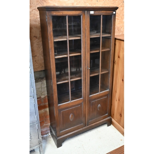 218 - An oak two door bookcase with glazed and panelled front, on bracket feet, 80 x 30 x 154 cm high