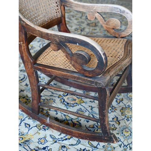 253 - An antique Continental rocking chair with caned back and seat, wooden frame with grained painted fin... 