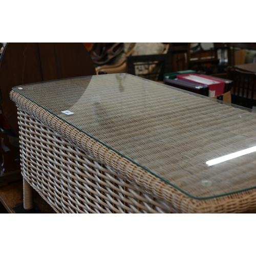 255 - A Laura Ashley rattan wicker glass top coffee table, 102 x 50 x 50 cm high