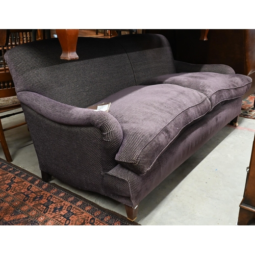 A modern Howard style three seat sofa, upholstered in Fleurons d'Helane Wilton damson fabric, raised on tapering mahogany front legs on brass castors, 184 cm w x 94 cm deep (the seat 64 cm deep x 50 cm h)