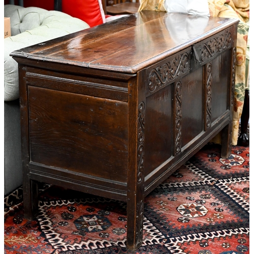 276 - An 18th century oak coffer, the staple hinged plank top over a relief carved triple panelled front, ... 