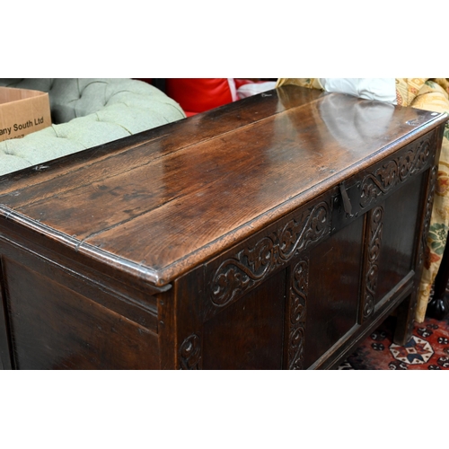 276 - An 18th century oak coffer, the staple hinged plank top over a relief carved triple panelled front, ... 