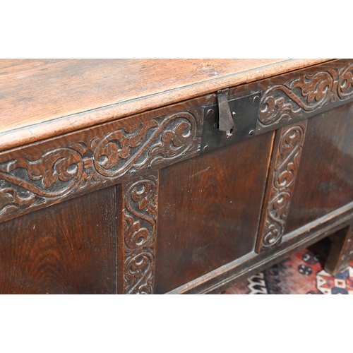 276 - An 18th century oak coffer, the staple hinged plank top over a relief carved triple panelled front, ... 