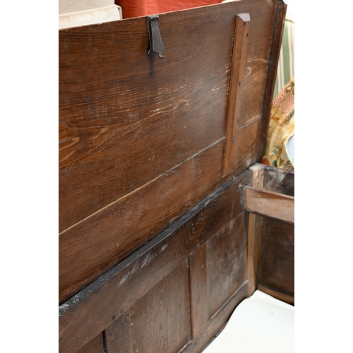 276 - An 18th century oak coffer, the staple hinged plank top over a relief carved triple panelled front, ... 