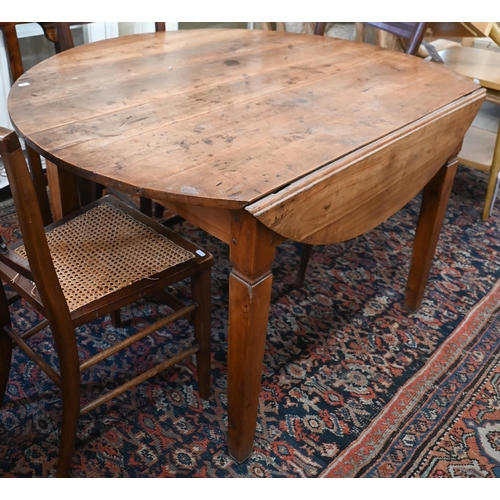 284 - # An antique continental cherry-wood drop leaf table, the circular top raised on shaped square legs,... 