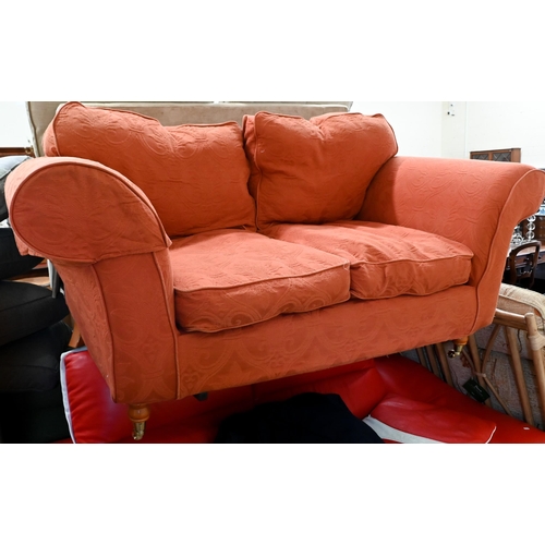 288 - # A modern two seat sofa, in pale terracotta loose covers, raised on turned feet and brass front cas... 