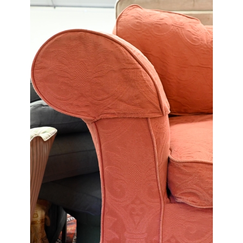 288 - # A modern two seat sofa, in pale terracotta loose covers, raised on turned feet and brass front cas... 