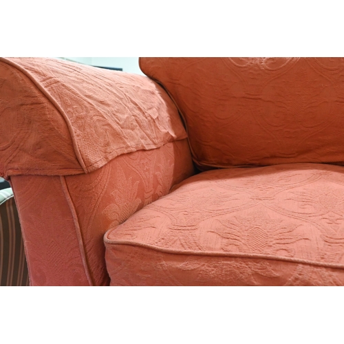 288 - # A modern two seat sofa, in pale terracotta loose covers, raised on turned feet and brass front cas... 