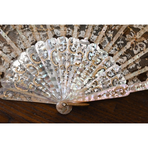 447 - An antique lace gauze fan, the central panel painted with cherubs, on decorated mother of pearl stic... 