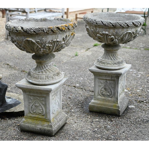 2 - A pair of weathered cast stone classical urns decorated with acanthus, raised on square plinths, 88 ... 