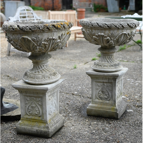 2 - A pair of weathered cast stone classical urns decorated with acanthus, raised on square plinths, 88 ... 