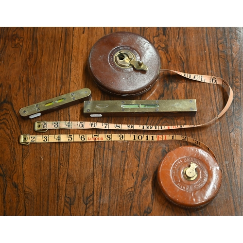 114 - Two vintage leather-cased measuring tapes - 100ft/66ft, to/w two brass-mounted wood spirit levels (4... 